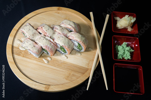 Sushi roll with salmon, cheese and avocado. Maki roll with shrimps fried, avocado and lattuce on a wooden plate . Delicious sushi rolls served on grey table