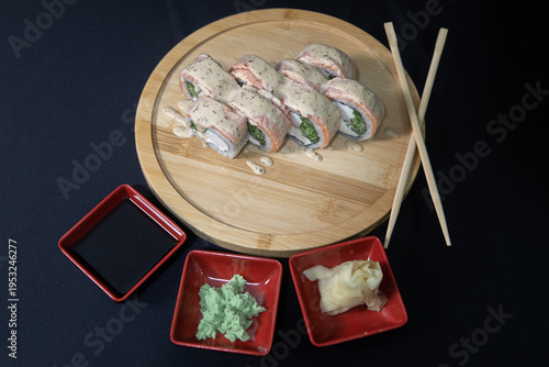 Sushi roll with salmon, cheese and avocado. Maki roll with shrimps fried, avocado and lattuce on a wooden plate . Delicious sushi rolls served on grey table