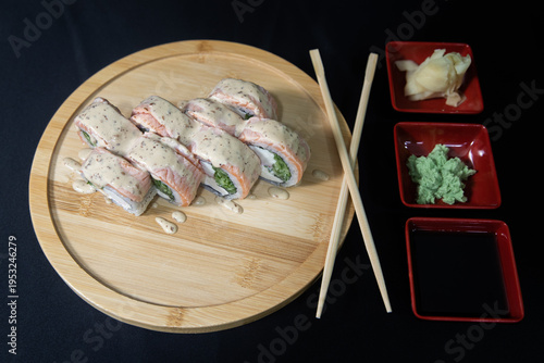 Sushi roll with salmon, cheese and avocado. Maki roll with shrimps fried, avocado and lattuce on a wooden plate . Delicious sushi rolls served on grey table