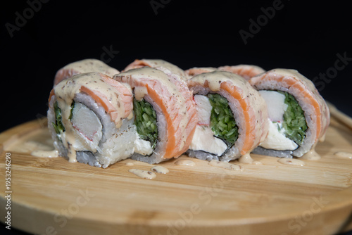 Sushi roll with salmon, cheese and avocado. Maki roll with shrimps fried, avocado and lattuce on a wooden plate . Delicious sushi rolls served on grey table