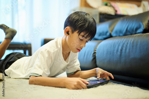 床でスマホゲームをする男の子