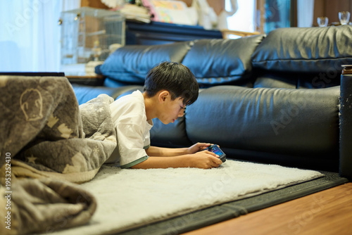 ソファ横の床でスマホに没頭する男の子