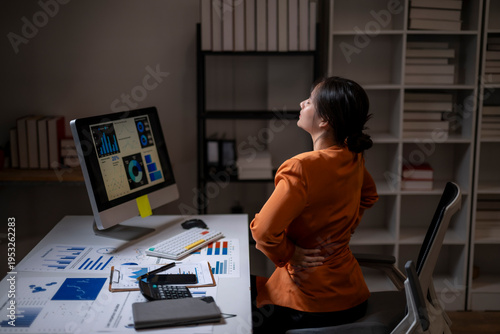 Foto Businesswoman experiencing back pain while working late at office
