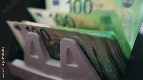 Close-up of one hundred euro bills in automatic money counting machine. Banking and finance concept.
