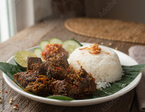 Traditional Indonesian Beef Rendang A Rich and Spicy Slow-Cooked Delicacy Served with Steamed White Rice, Fresh Cucumber, and Chili Sauce