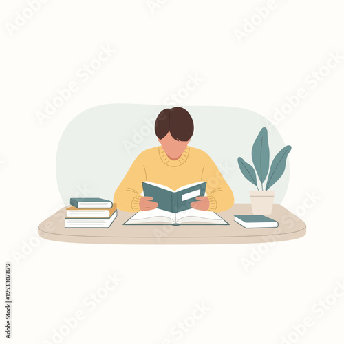 Young adult reading book sitting desk.