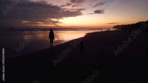 Silhouette of a mother and her little daughter playing on the beach at sunset