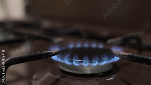 A man lights a gas stove burner using a match in the kitchen. The process of lighting domestic gas on a kitchen stove with a lit match, the appearance of a blue flame on the burner