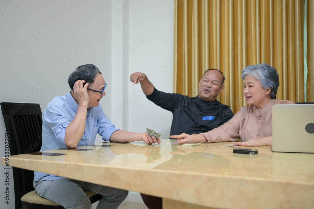 Fototapeta premium Group of mature friends playing cards together at a table