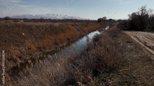 lonely river, rural open spaces, autumn landscape, a light breeze sways the grass, snow-capped mountains in the background