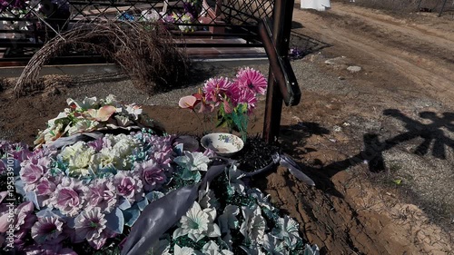 memorial artificial flowers on the grave and a glass cup, medium plan