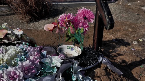 funeral artificial flowers on the grave and glass cup, close-up