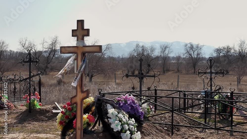 the wind flutters a funeral scarf on a cross in an old rural cemetery against the backdrop of mountains, medium plan
