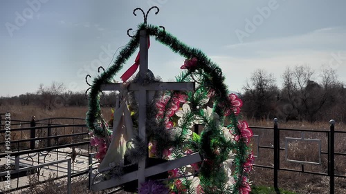 the wind sways the funeral wreath on the cross in the old rural cemetery