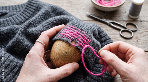 Visible mending on wool sweater with bright yarn