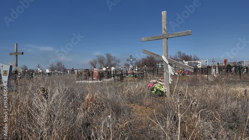 view of an old abandoned unmarked rural grave against the backdrop of dried grass that is swayed by the wind in the background
