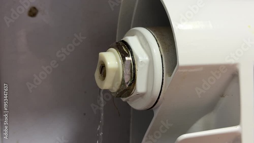 Wallpaper Mural A flat-head screwdriver is inserted into the bleed valve of a white household radiator to release trapped air. Water droplets are visible beneath the valve Torontodigital.ca