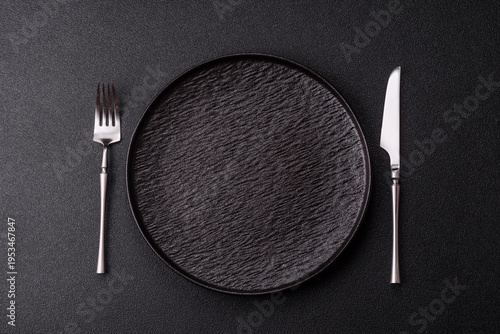 An empty round ceramic plate, knife, and fork as a dining table setting. An empty plate