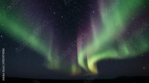 Northern Lights display with vibrant green and purple auroras illuminating the night sky over a dark landscape, showcasing a stunning celestial phenomenon