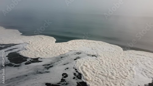 Ocean waves create foam patterns along the rocky shoreline, with misty atmosphere enhancing the tranquil coastal scene captured in three sequential frames