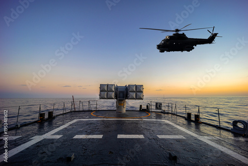 A helicopter flies over a warship during a naval exercise in mediterranean sea.