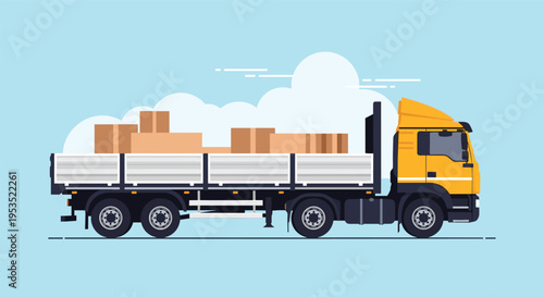 Large yellow cargo truck transporting cardboard boxes on open flatbed trailer driving on highway under blue sky.