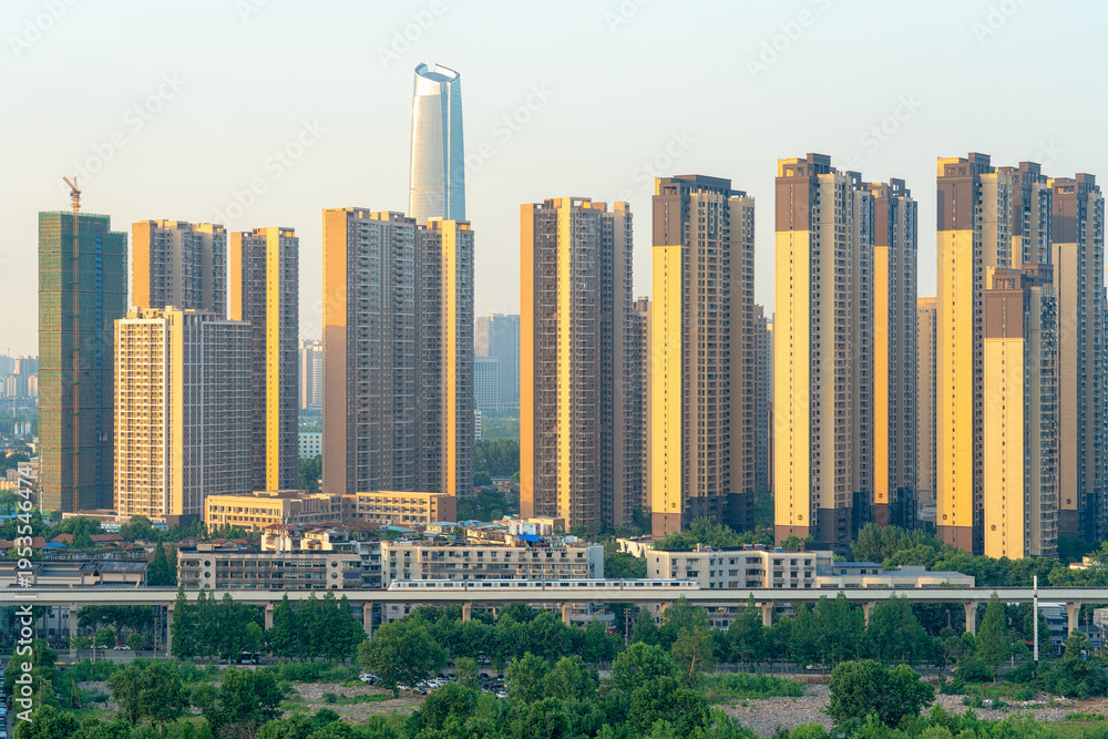 Fototapeta premium High-Speed Train Passes Through Urban Neighborhood with Modern Tower Developments