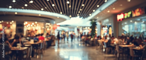 Blurry image of a busy food court inside a modern shopping mall with people dining.