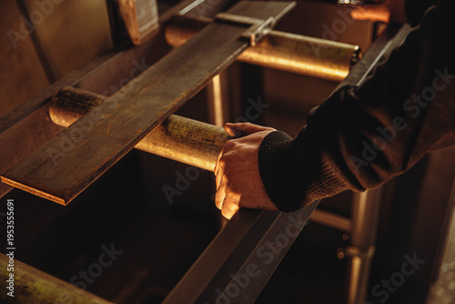 Tableau sur toile Close-up of a worker's hand moving metal parts on industrial rollers in a workshop