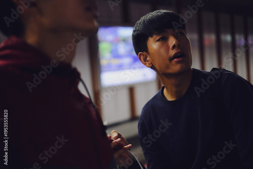 Young Asian Man Looking Up at Information Screen in Modern Transit Station