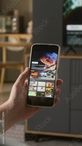 Vertical close-up of hand of anonymous man holding smartphone with dystopian sci-fi movie trailer on video streaming app, while eating chips, leisure and mobile entertainment concept