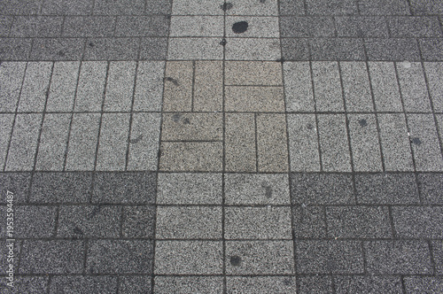Texture of square paving tile. Pattern of tiles in the street. Close up of grey, brown, and beige concrete pavers background.	