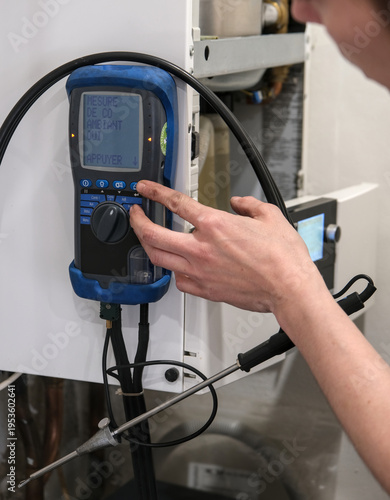 Fotografie Technician adjusting digital measuring device on residential boiler, checking ambient carbon monoxide levels with probe sensor