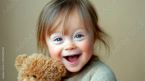 Cute caucasian toddler girl with down syndrome smiling and holding teddy bear in soft light minimal background