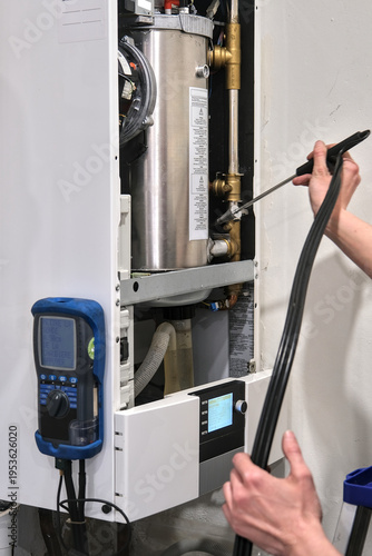 Technician inspecting residential boiler interior using probe device, checking gas levels and ensuring safe operation of home heating system.