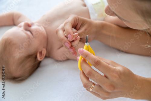 Mother cutting baby's nails with safety scissors, concept of hygiene and infant care.