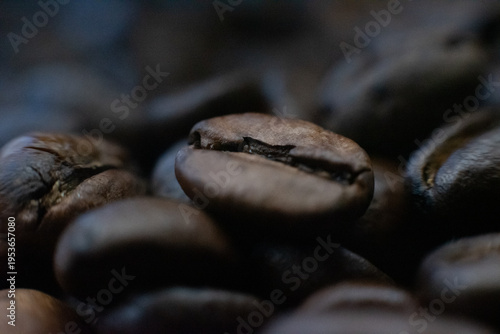 Macro close up of roasted coffee beans with shallow depth of field and dark moody lighting.