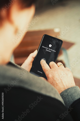 Fingerprint biometric authentication on smartphone. Senior woman unlocking phone with touch ID. Cybersecurity and digital inclusion concept.