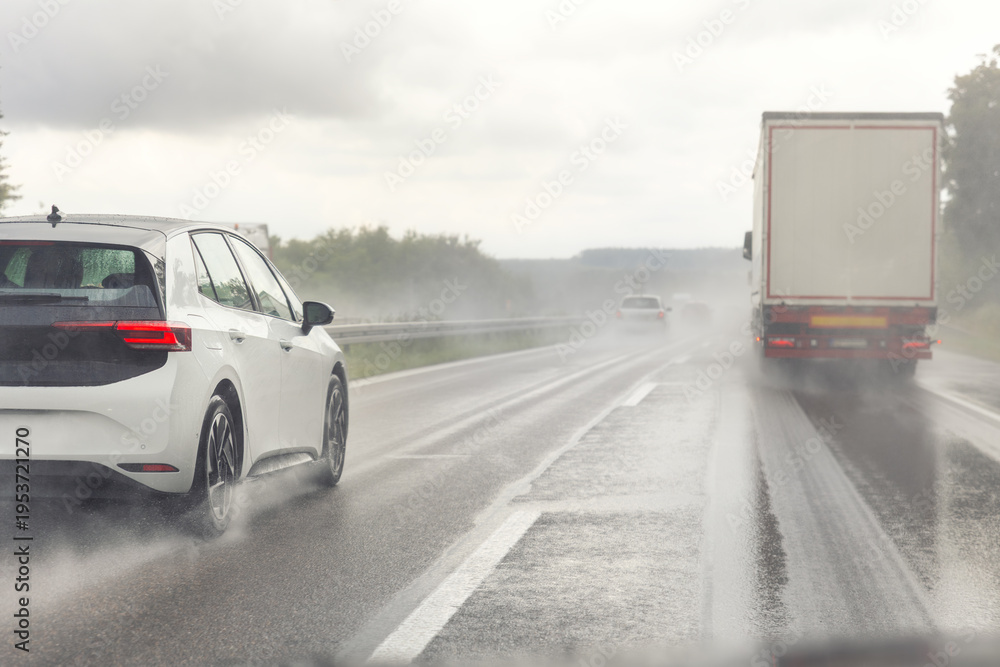 Obraz premium Back tail view of many cars driving fast on wet highway road after rain in Europe. Automobile accident vehicle rush hour collapse. Transportation vacation seasonal stuck. Low visibility bad weather