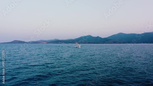 White Yacht Cruising on Blue Sea with Mountain Range at Dusk