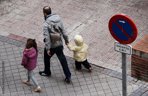 Bild auf Leinwand Padre con sus hijos pequeños de la mano acompañando camino del colegio