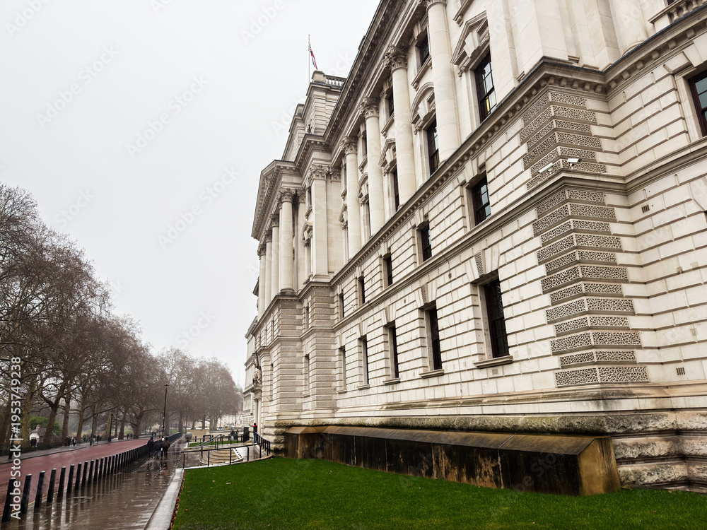 Fototapeta premium Neoclassical His Majesty's Treasury government building with columns and wet street in London, UK on an overcast day