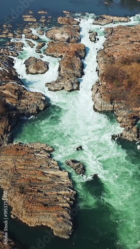 Dynamic aerial shot of the powerful Khone Falls cascading through rocky terrain in Laos, showcasing dramatic water flow and rugged natural beauty.