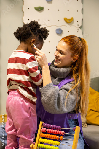 Fotografi Teacher caring for african american girl in nursery school