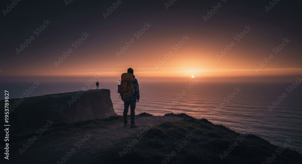 Fototapeta premium Hiker overlooks sunset over ocean
