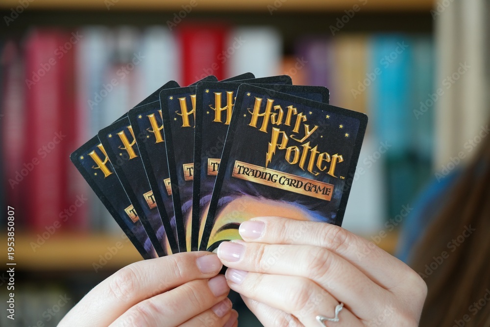 Fototapeta premium WARSAW, POLAND - MARCH 19, 2026: Person holding a hand of Harry Potter Trading Card Game, a collectible card game based in the world of Harry Potter novels. It was published by Wizards of the Coast.