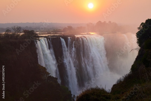 Photos Spectacular sunrise over Victoria Falls (Mosi-oa-Tunya) with mist and golden sunlight, Zambezi River, border of Zambia and Zimbabwe