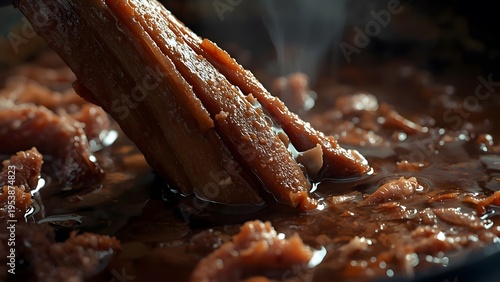 Simmering savory beef in a rich dark sauce with a wooden spoon stir