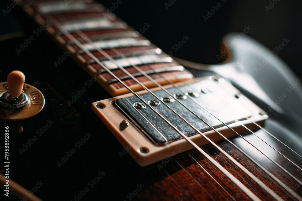 Fototapeta premium A guitar rests on a wooden table with soft light highlighting its body and strings. Knobs and switches catch the light. The room has a warm atmosphere as music fills the air