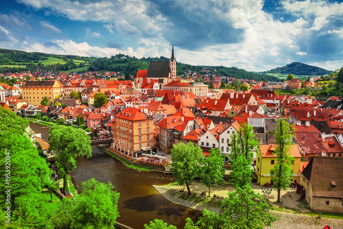 A stunning aerial drone view of Cesky Krumlov in the Czech Republic, showcasing its historic old town, red rooftops, and the winding Vltava River. This UNESCO World Heritage site features picturesque 